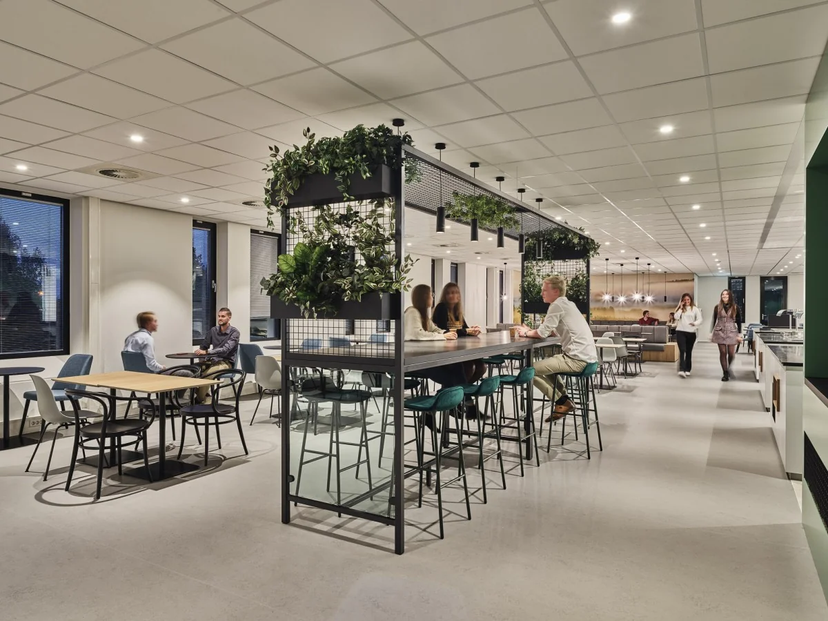 Moderne en open kantoorkantine aan de Van Deventerlaan 31-51 met mensen die aan tafels zitten en rondlopen.