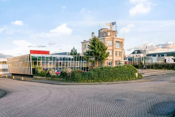 Kantoorgebouw met moderne glazen gevel in Maassluis, omringd door groen en een rustige straat.