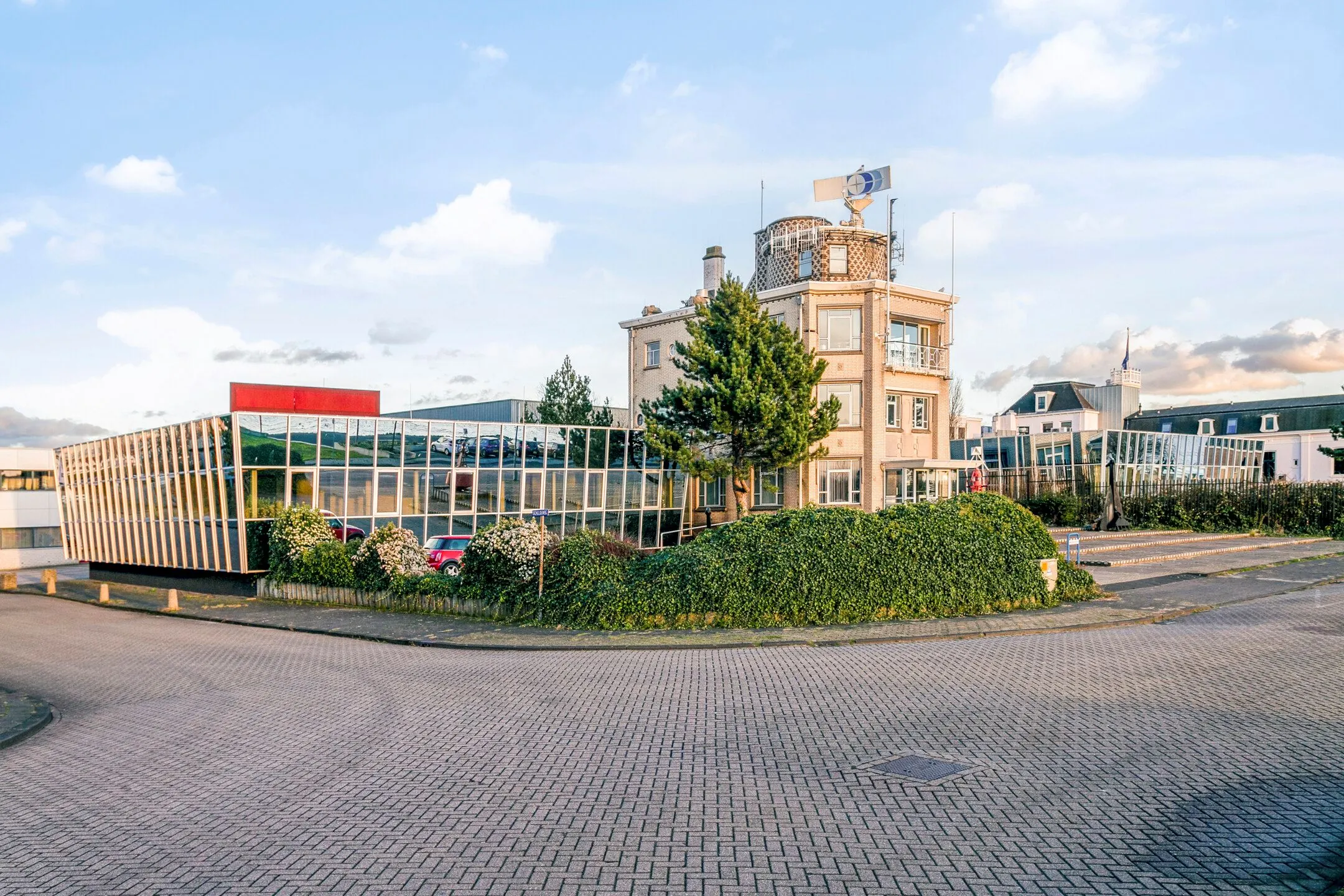 Kantoorgebouw met moderne glazen gevel in Maassluis, omringd door groen en een rustige straat.