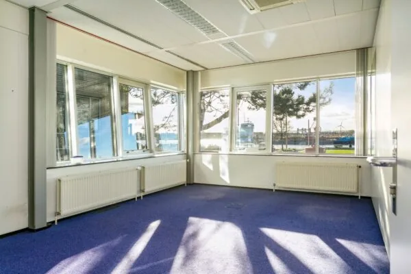 Licht kantoor met blauwe vloerbedekking en uitzicht op de haven van Maassluis.
