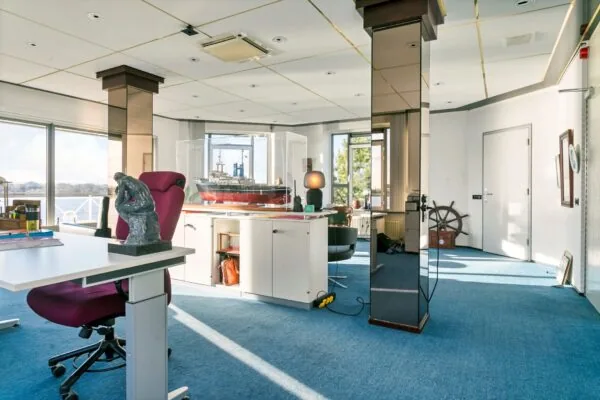 Modern kantoor met maritieme decoratie, waaronder een groot modelschip en een houten scheepsstuurwiel, in Maassluis.