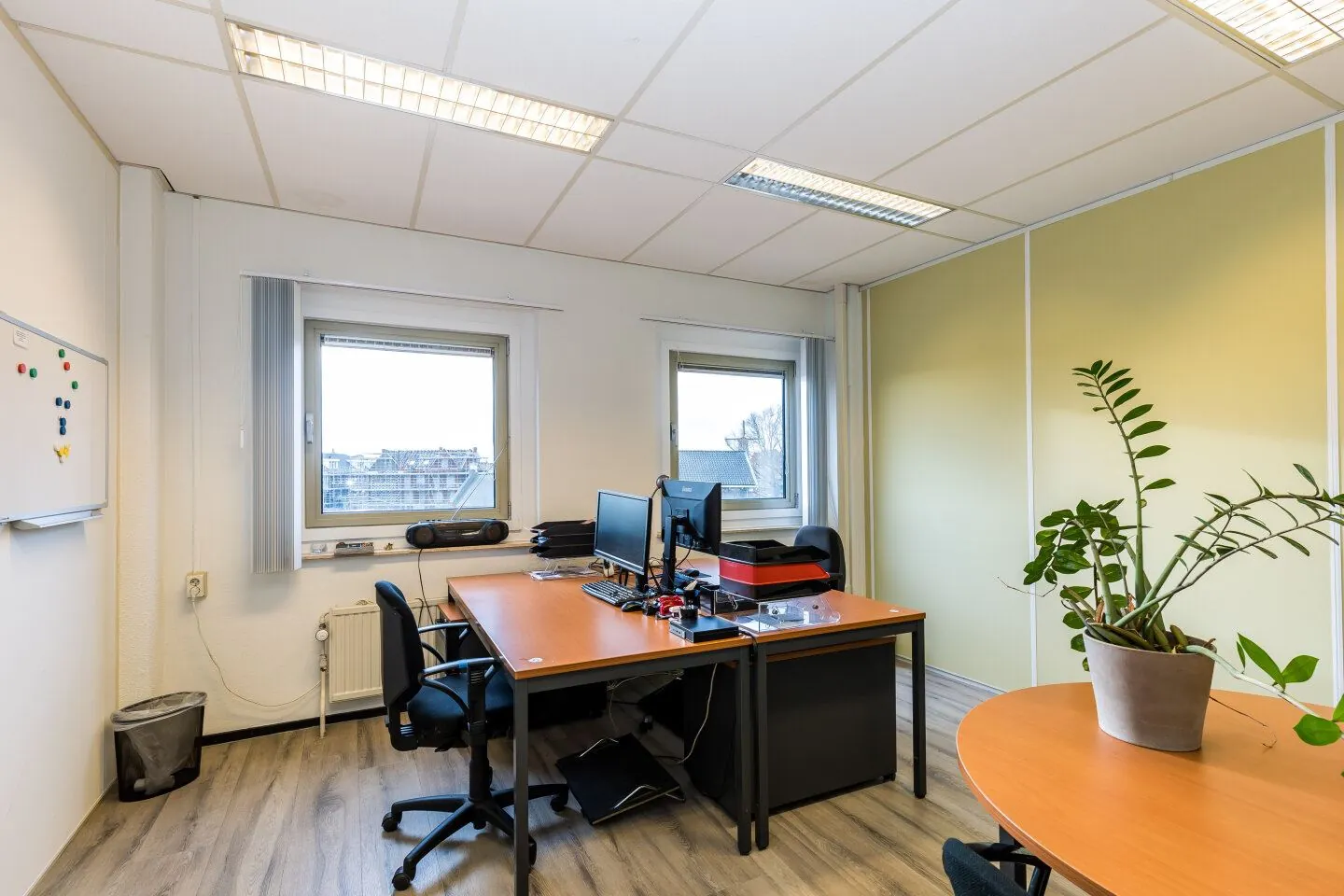 Klein, licht kantoor in het gebouw aan de Noordvest in Schiedam met twee bureaus, computers en een grote kamerplant.