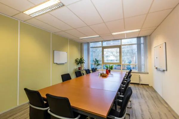 Vergaderruimte met lange tafel, tien stoelen, whiteboards en uitzicht op Noordvest in Schiedam.