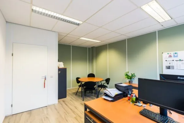 Modern ingerichte kantoorruimte in Schiedam met bureaus, vergadertafel en groene wanden.