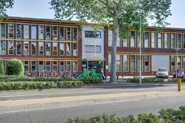 Vooraanzicht van een modern kantoorpand aan de Groenestraat 294 met fietsenstalling en ingang.