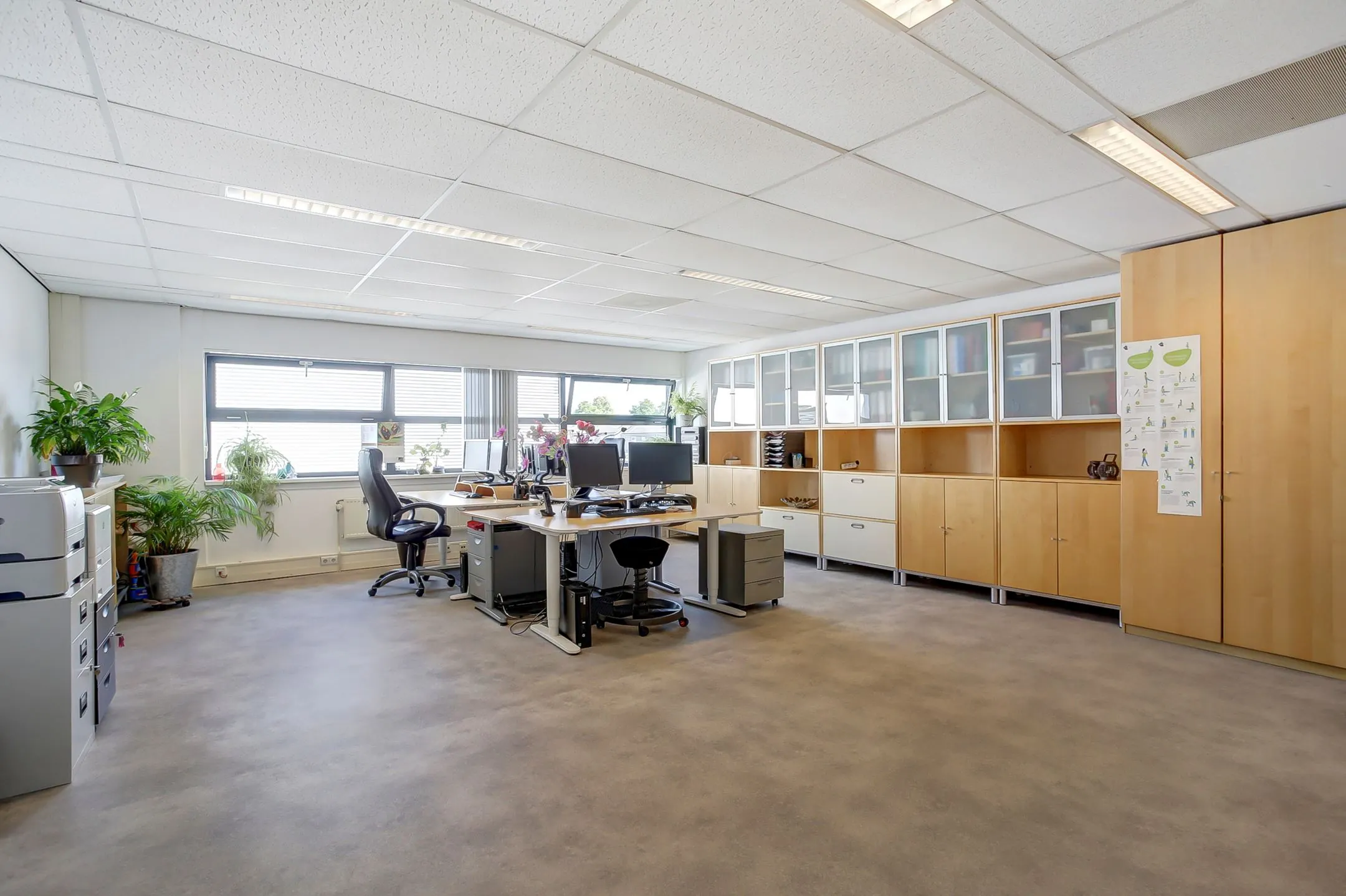 Ruim en licht kantoor met bureaus, kasten en grote ramen aan de Groenestraat 294.