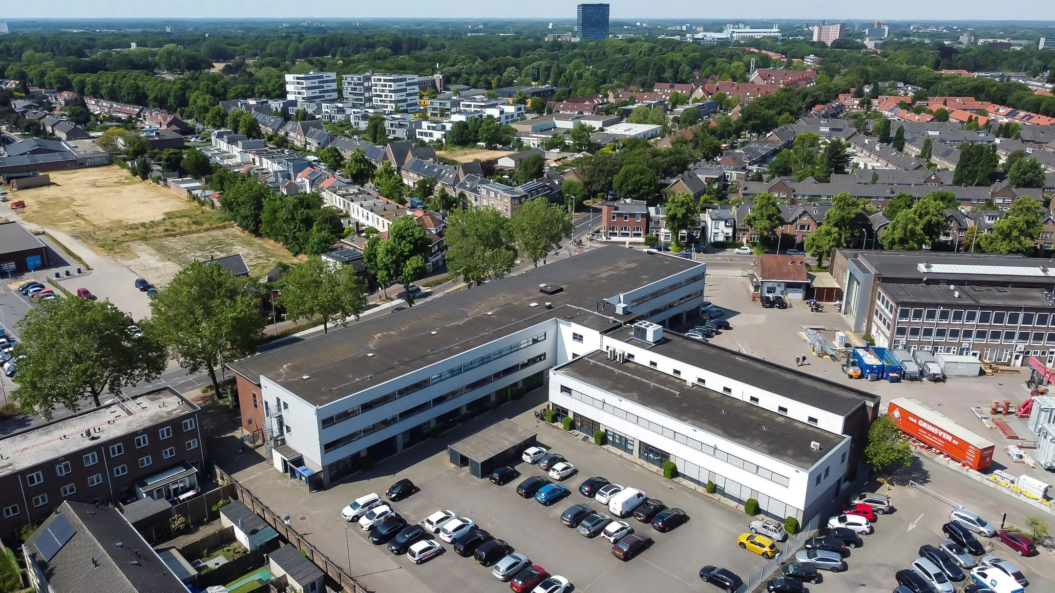 Luchtfoto van een wit bedrijfsverzamelgebouw aan de Groenestraat 294 met parkeerterrein en omliggende woonwijk.