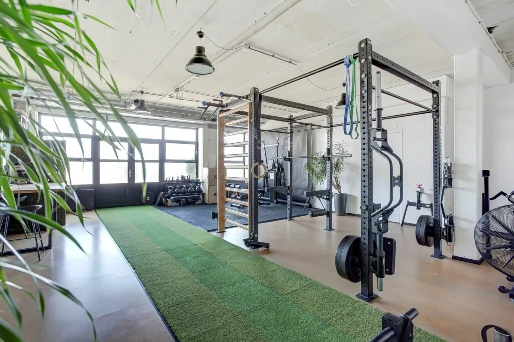 Moderne en lichte fitnessruimte aan de Groenestraat 294 met krachttoestellen, kunstgrasbaan en trainingsmaterialen.