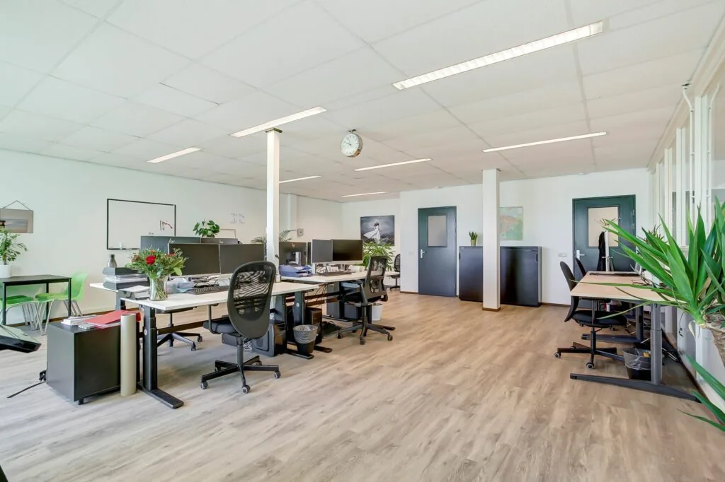 Modern en licht kantoorinterieur aan de Groenestraat 294 met meerdere werkplekken en groene accenten.
