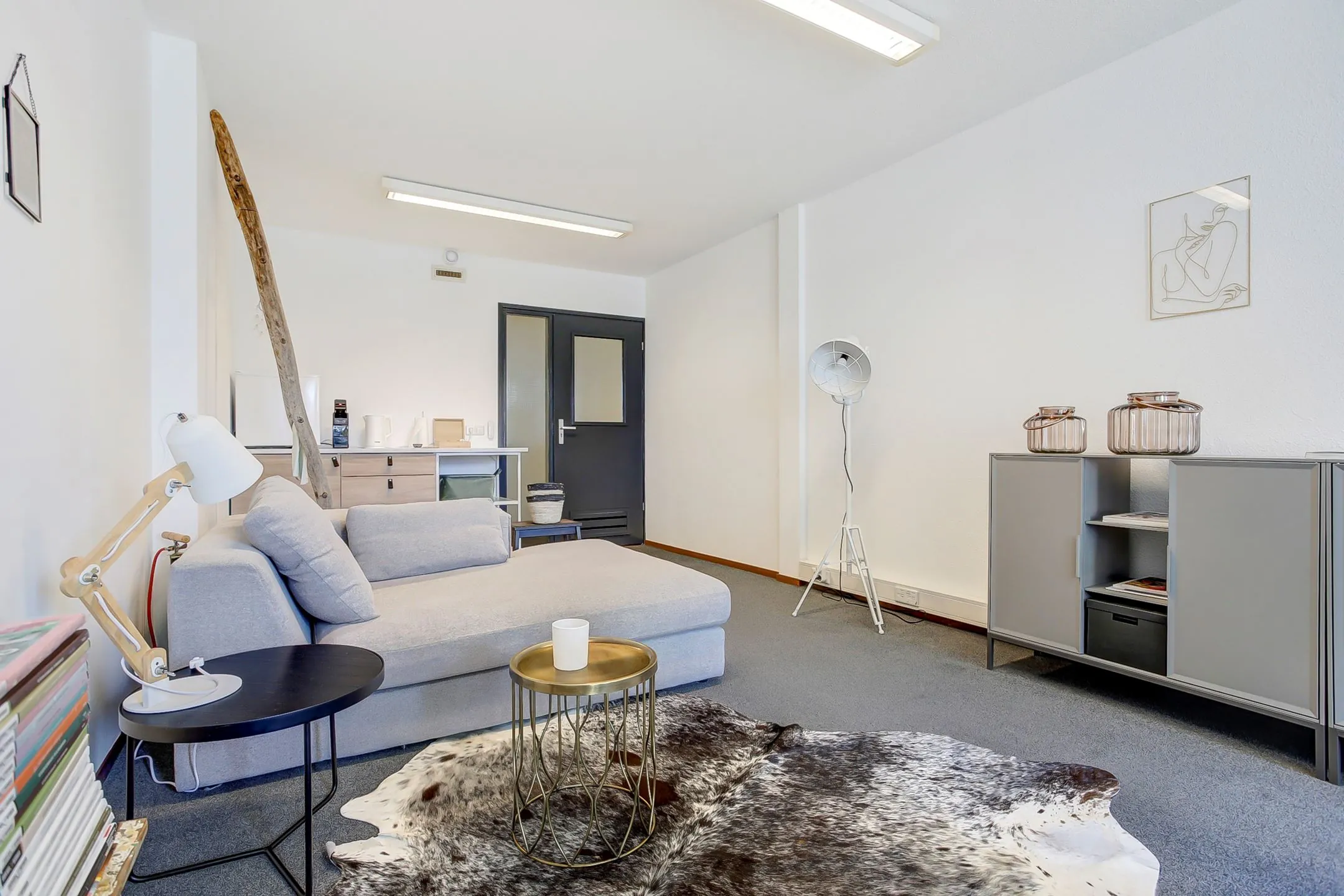 Stijlvol ingerichte woonkamer van huurappartement Groenestraat 294-7 met een moderne hoekbank, vloerkleed van koeienhuid en minimalistische decoratie.