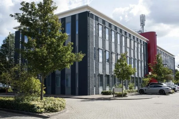 Modern kantoorgebouw aan de Kerkenbos 1033-1037 met parkeerplaatsen en omliggend groen.