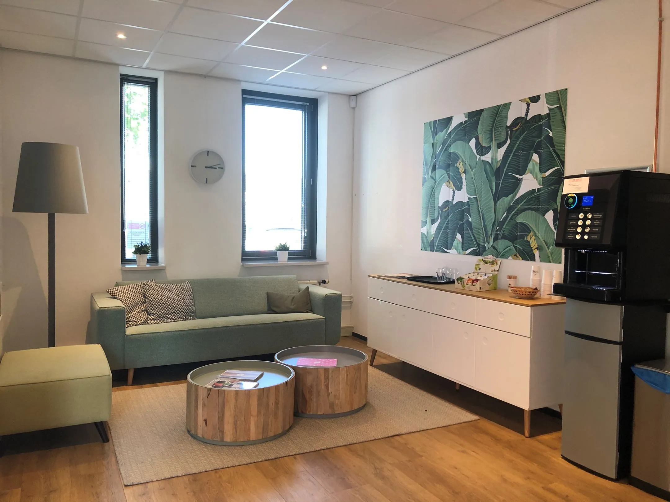 Gezellige wachtruimte in Kerkenbos 1033-1037 met zitbank, koffietafel, koffieautomaat en groene wanddecoratie.