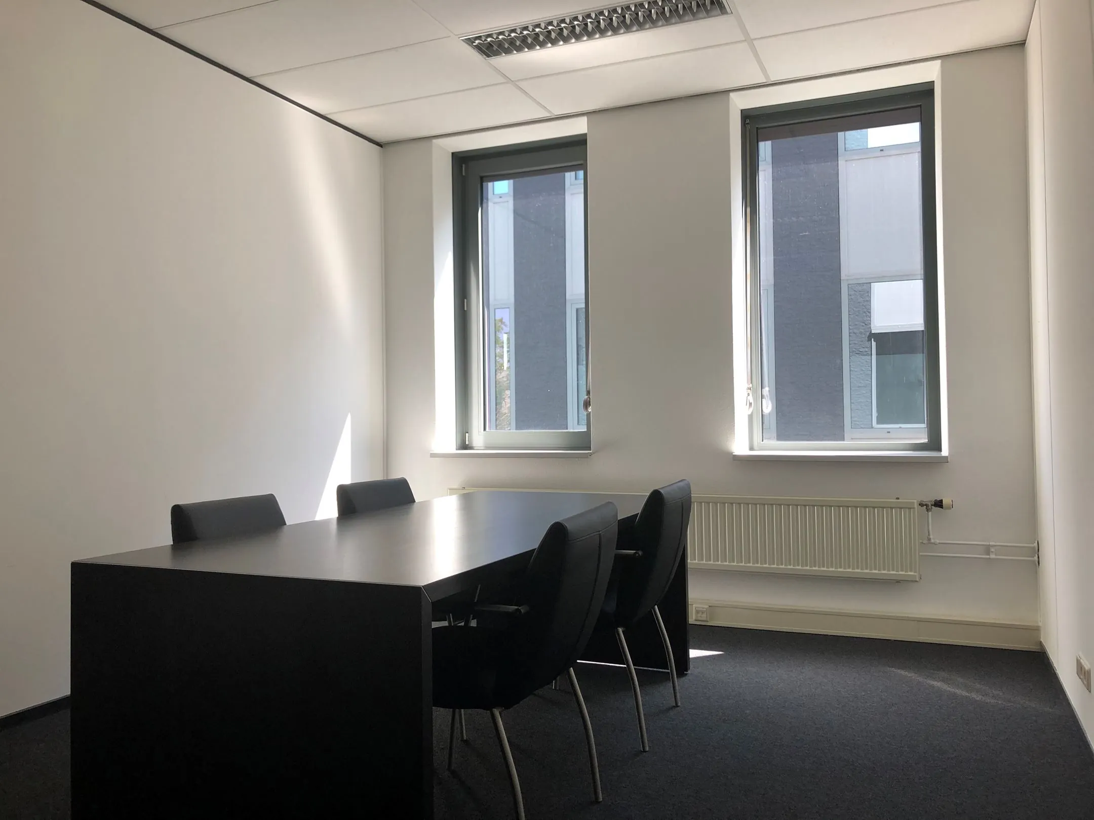 Kleine vergaderruimte in kantoorpand Kerkenbos 1033-1037 met tafel, zes stoelen en twee ramen.