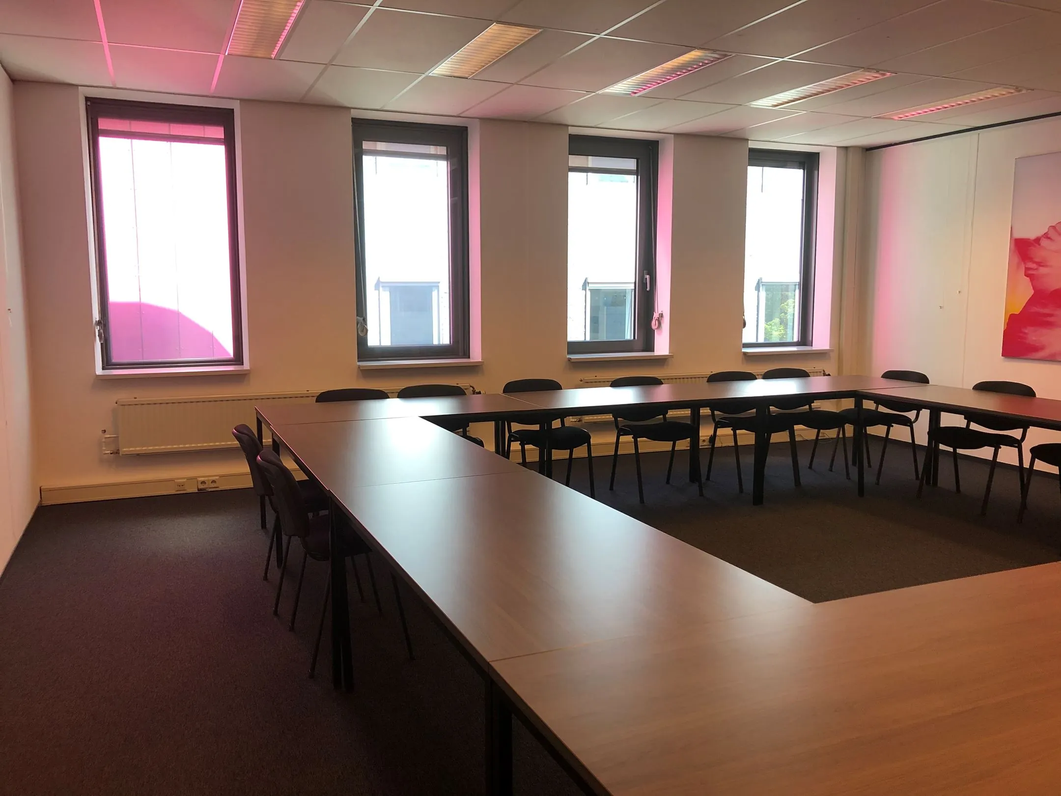 Vergaderruimte met U-vormige opstelling van tafels en zwarte stoelen in gebouw Kerkenbos 1033-1037.