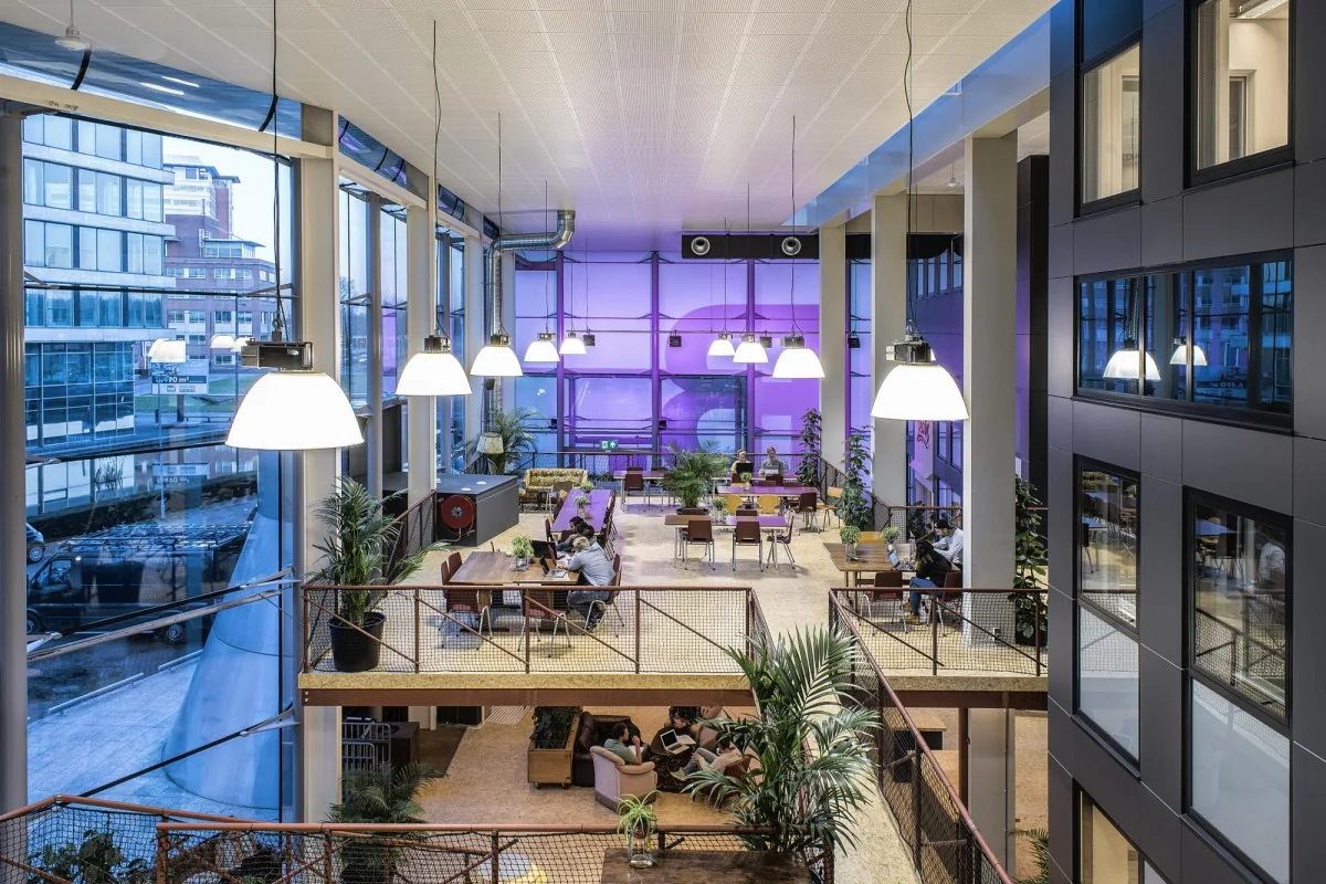 Moderne, open kantoorruimte met hoge ramen en werkplekken aan het John M. Keynesplein in Amsterdam.