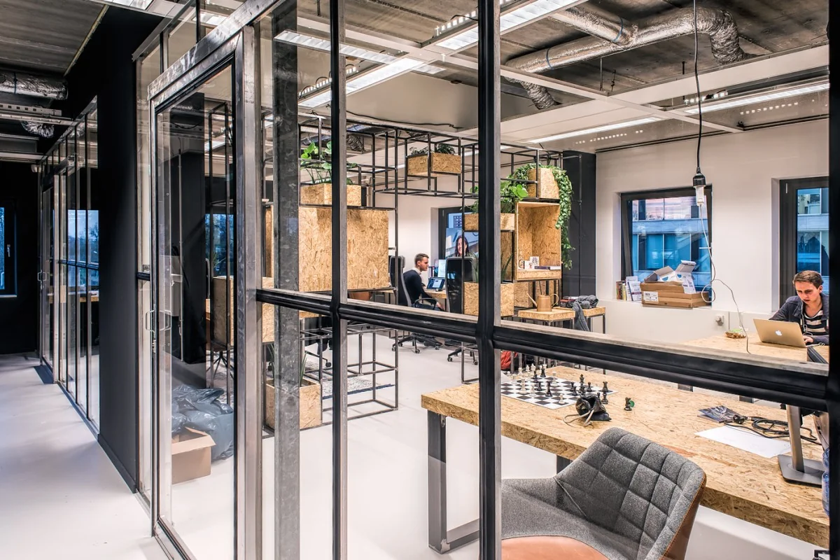 Moderne kantoorruimte aan het John M. Keynesplein in Amsterdam met industriële inrichting, werkplekken en een schaakbord op tafel.