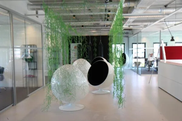 Moderne kantoorruimte aan het John M. Keynesplein in Amsterdam met futuristische zitstoelen en hangende groene decoratie.