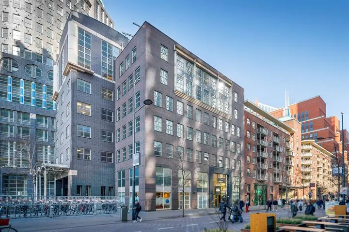 Moderne kantoorgebouw Turfmarkt 104 in een levendige stadsomgeving met voetgangers en fietsenstalling.