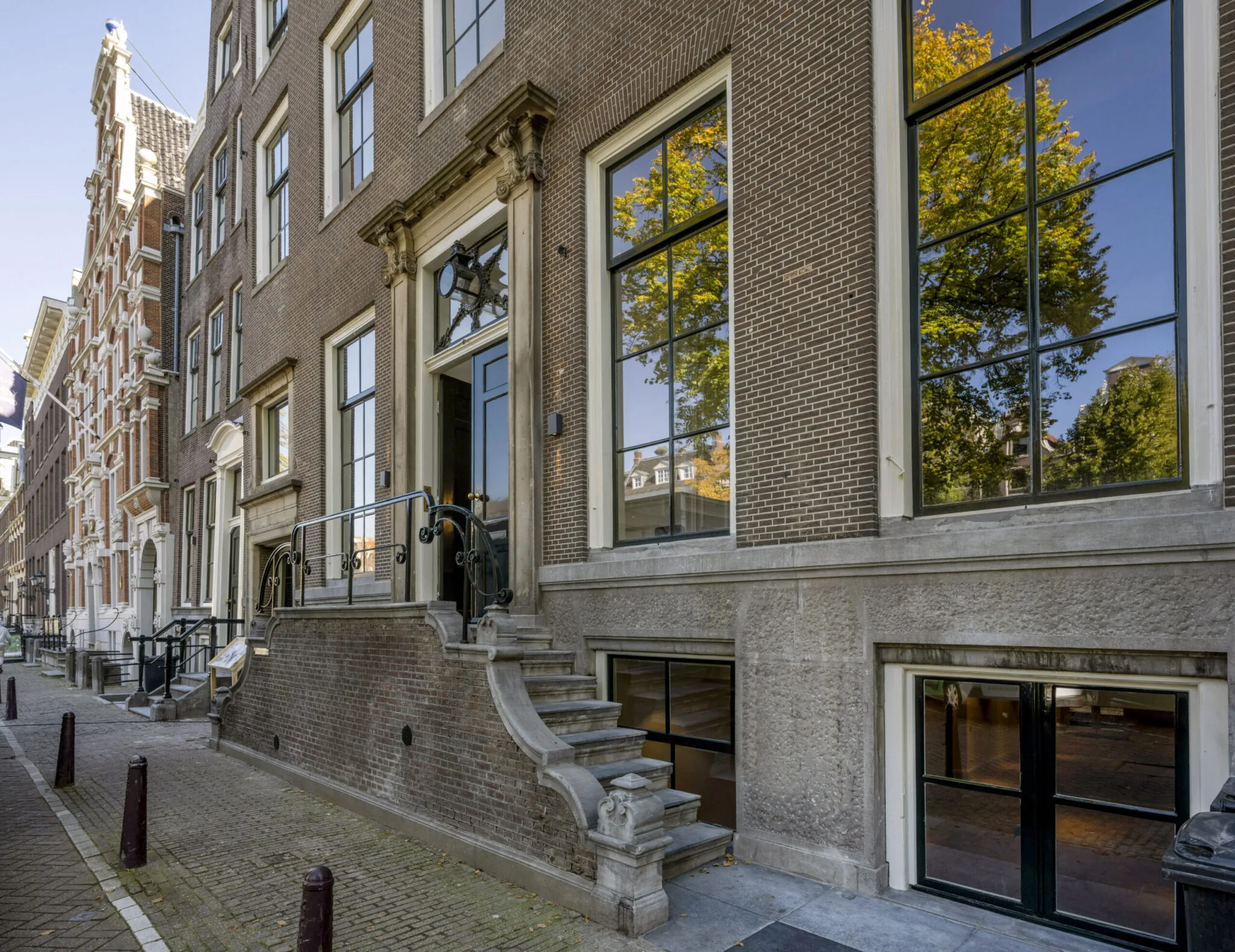 Voorgevel van een klassiek Amsterdams grachtenpand met hoge ramen en monumentale ingang.