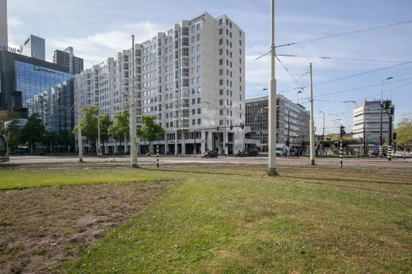 Wit appartementencomplex Weena 113 met omliggende moderne kantoorgebouwen en tramlijnen in Rotterdam.