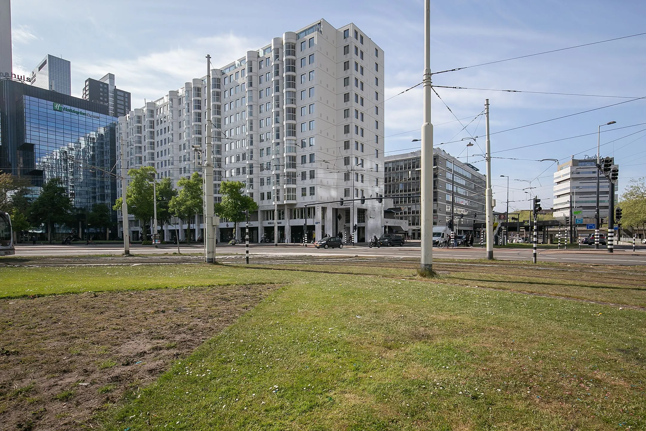 Wit appartementencomplex Weena 113 met omliggende moderne kantoorgebouwen en tramlijnen in Rotterdam.