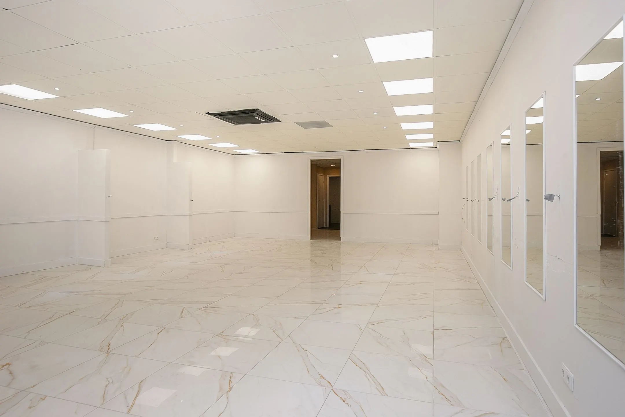 Lichte, lege commerciële ruimte aan de Weena 113 met marmeren vloertegels, spiegelwand en systeemplafondverlichting.