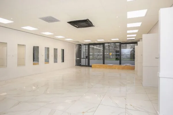 Lichte, lege winkelruimte aan de Weena 113 met marmeren vloer, grote ramen en plafondverlichting.