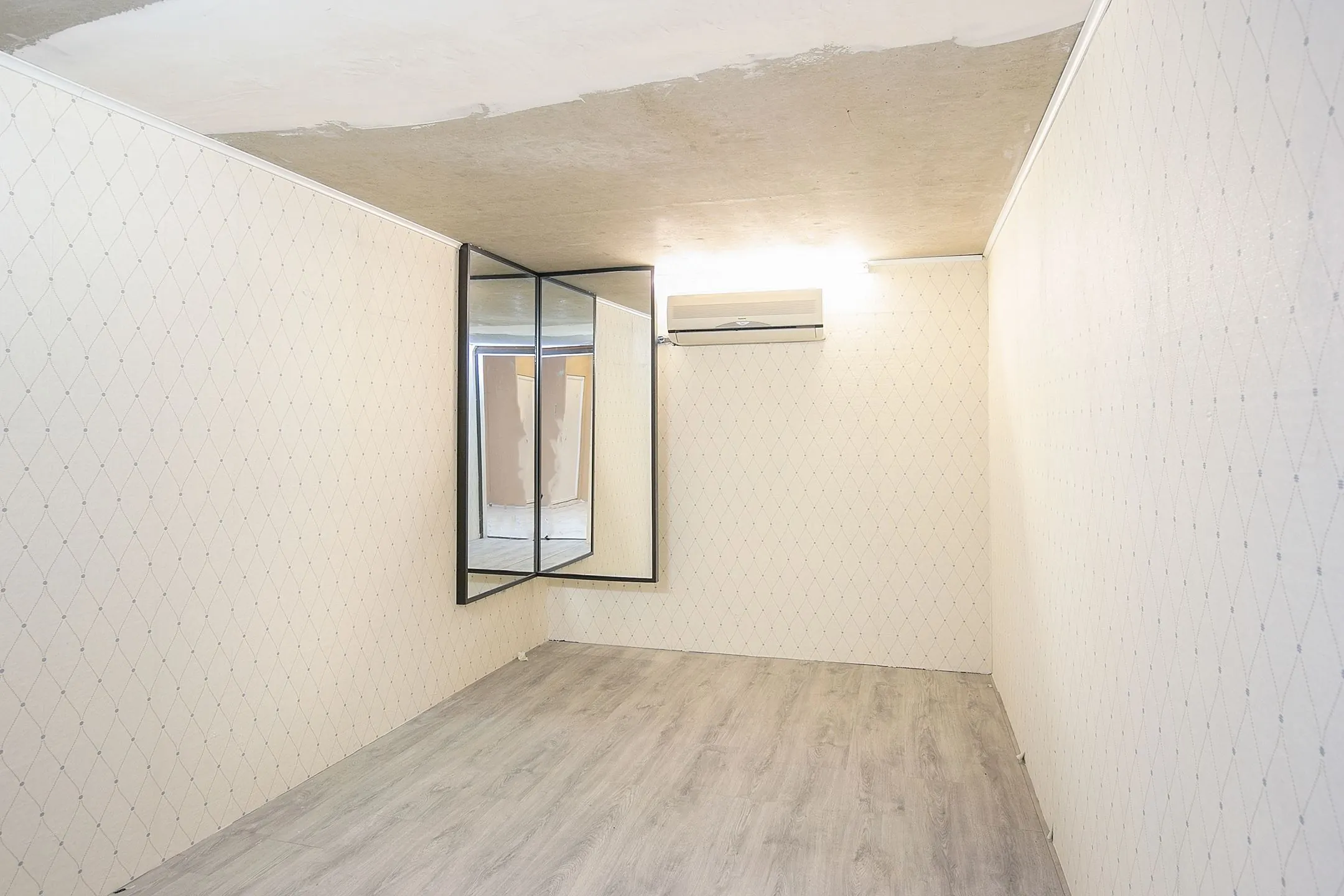 Lege kamer in Weena 113 met licht houten vloer, gespiegeld hoekraam en airconditioning aan de muur.