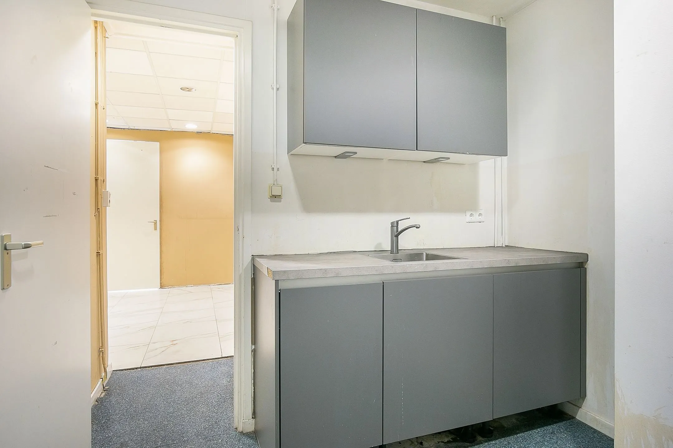 Kleine pantry met grijze keukenkastjes en een betonnen werkblad, gelegen in het pand Weena 113.