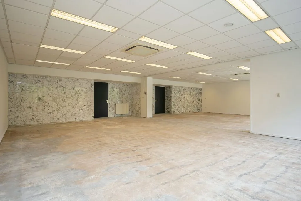 Leeg kantoorpand aan Weena 75 met afgewerkte plafonds, marmerlook wandpanelen en kale vloer.
