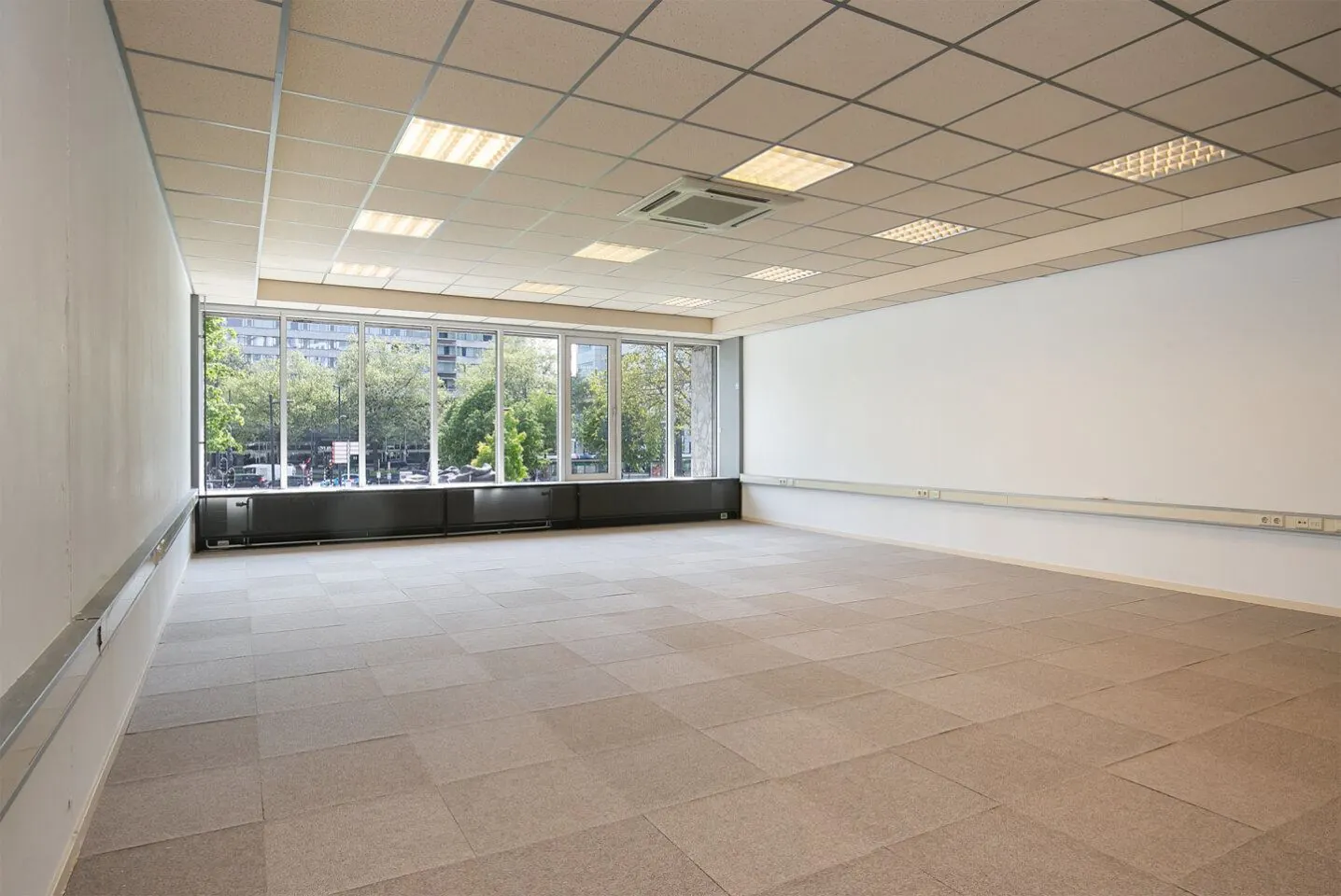 Lichte, lege kantoorruimte met systeemplafond en grote ramen aan de Weena 81.