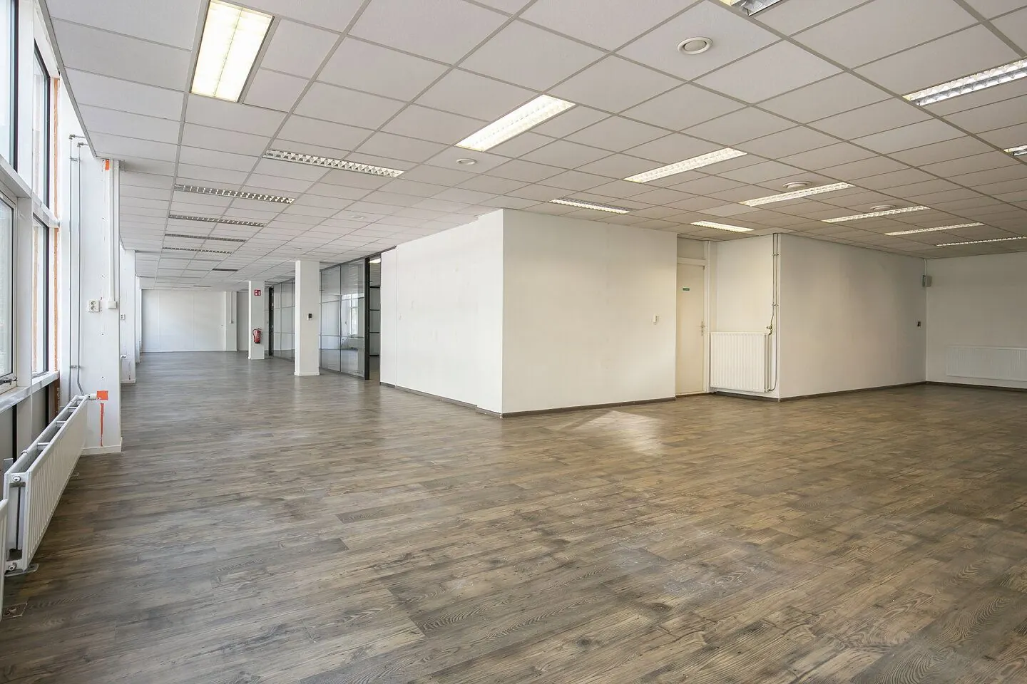 Ruime, lege kantoorruimte in Weena 81 met houten vloer, systeemplafond en grote ramen.